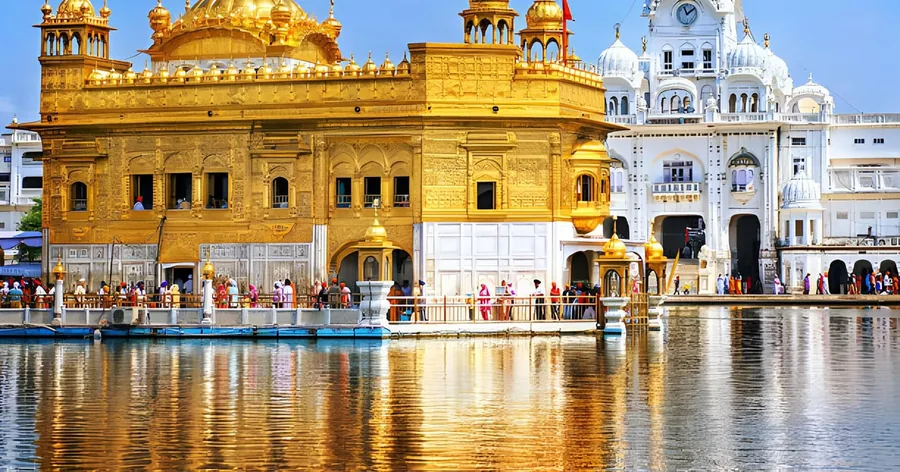 तेज़ धूप में सुनहरा गर्भगृह और उसके पीछे सफ़ेद इमारतें, सरोवर के किनारे परिक्रमा पर श्रद्धालु