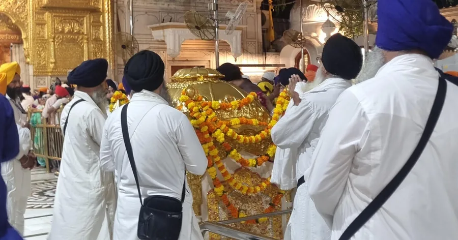 सफ़ेद और केसरिया कपड़ों में श्रद्धालु, मंदिर परिसर में एक सुनहरी पालकी के साथ चलते हुए
